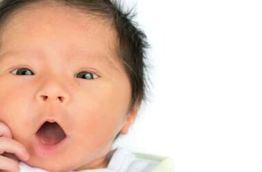 A surprised newborn baby on a white background